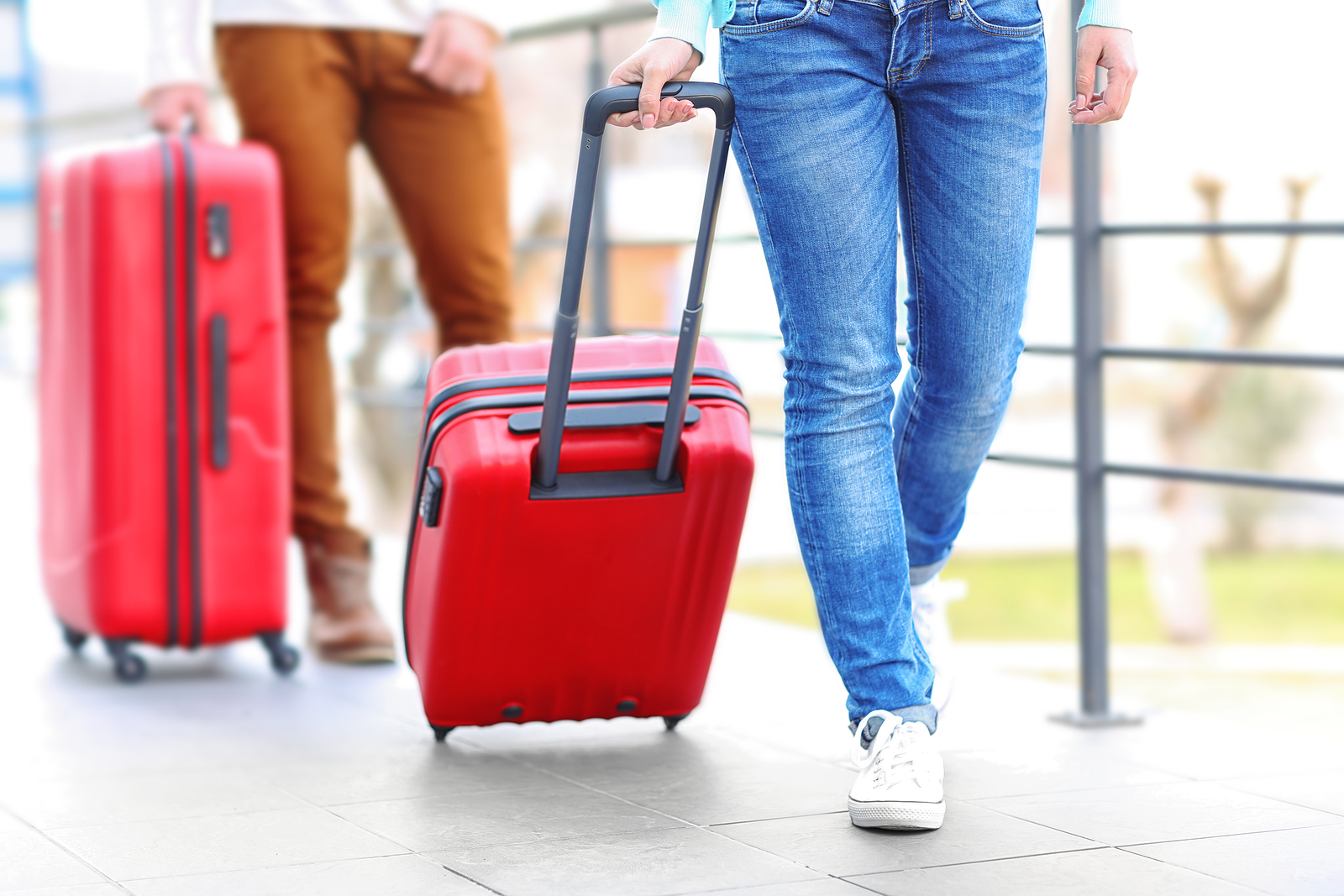 Couple rolling large red suitcases, close up