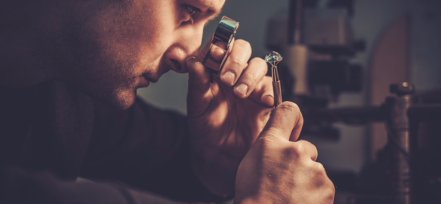 Jeweler looking at the ring through microscope in a workshop.