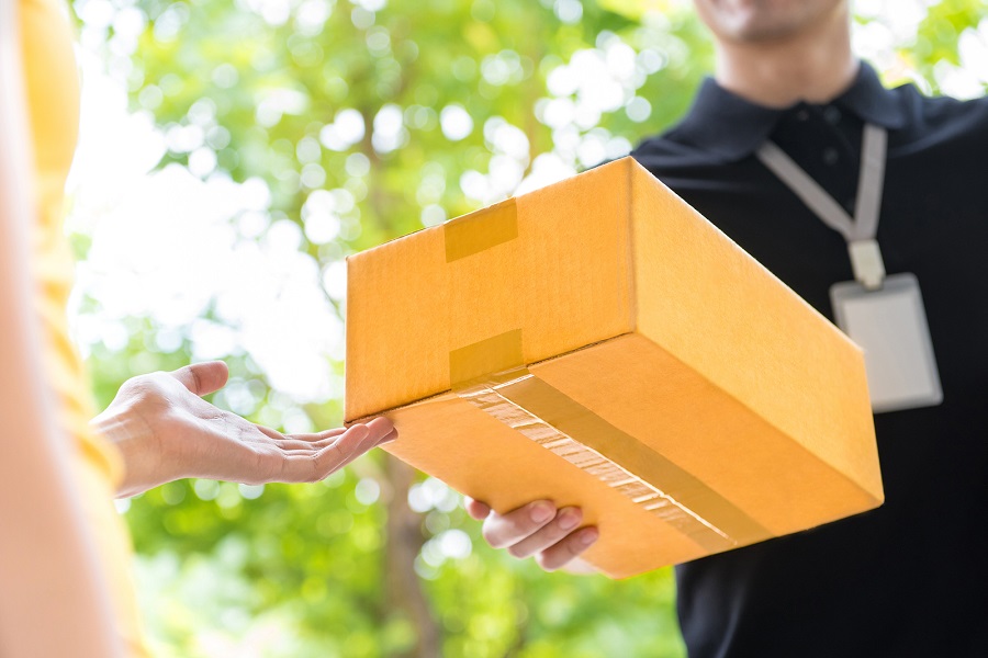 Delivery man delivering package to customer close up at hand and box