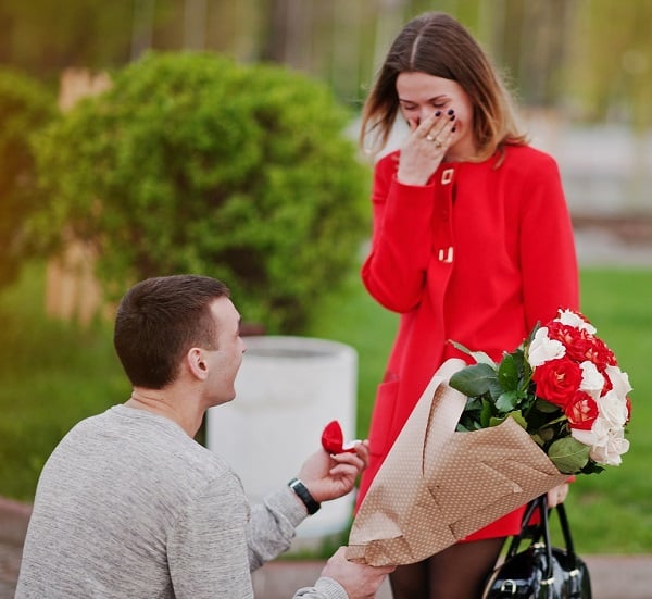 Marriage Proposal. Man With Boquet Of Flowers Kneeling And Give