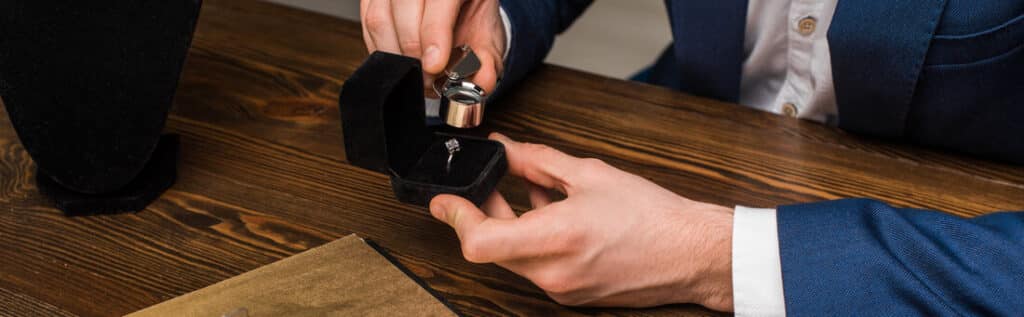 Appraiser examining diamond ring with magnifying glass