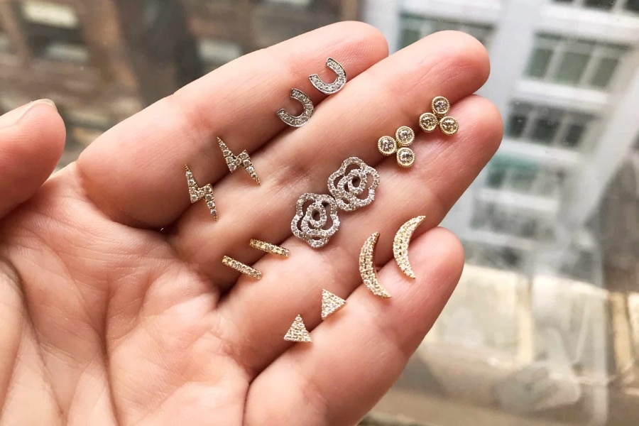 hand holding various diamond earrings