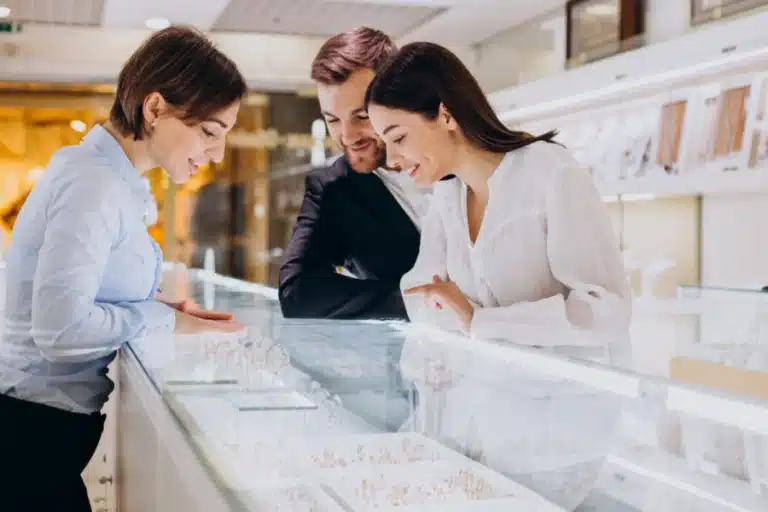 A couple who wants to buy a diamond safely looks at diamond engagement rings in a jeweler’s display case.