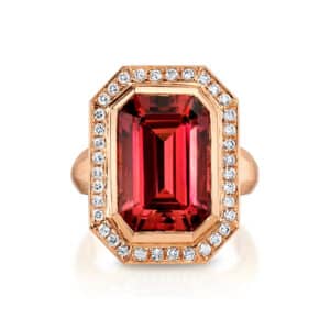 An emerald-cut orange-red tourmaline ring with a diamond halo in rose gold, by Omi Prive.