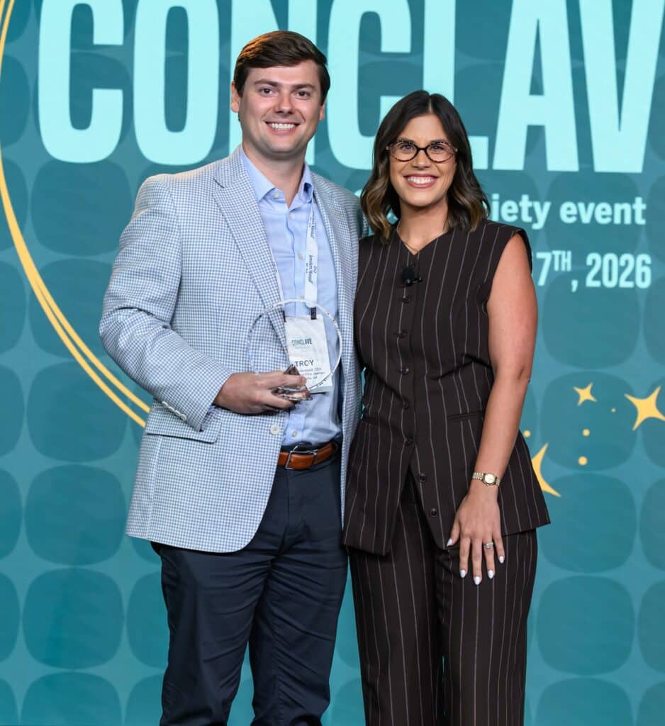 Troy Underwood posing with an award recipient in front of a Conclave 2026 backdrop.